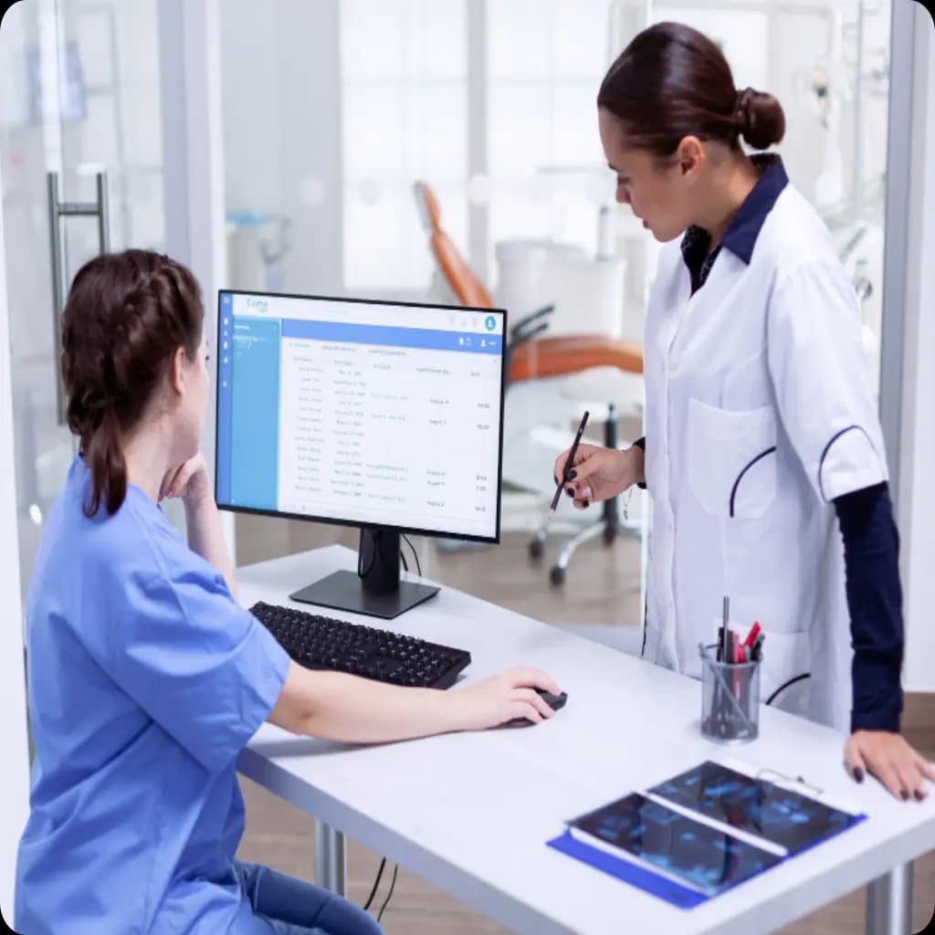 Two medical professionals looking at a computer screen.